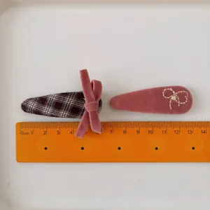 Set of two pink velvet and plaid bow hair clips for girls shown with a metric ruler