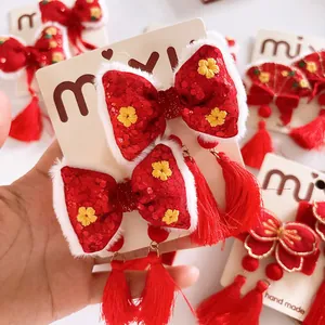 Detalle de pinza para pelo con lazo rojo, borla, bordado y ribete de piel para Año Nuevo