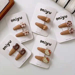 Detailed view of brown fabric BB hair clips with floral and cartoon bear embroidery