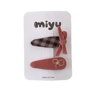 Set of two pink plaid velvet bow hair clips for girls on a white display card