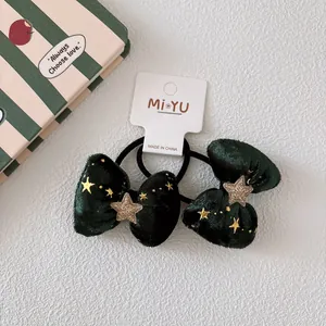 Dettaglio di elastici in velluto verde scuro con stelle di paillettes dorate su carta
