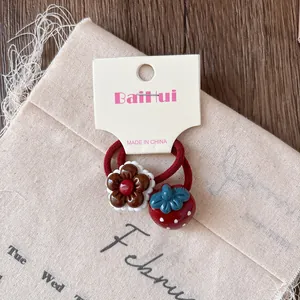 Close-up of cute red kids hair ties with resin strawberry and chocolate flower charms