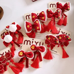 Detalle de pinzas para el pelo rojas de Año Nuevo con borlas, bordados y bordes de felpa