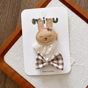Detail of cute leather bunny and plaid bow hair clips set for girls on a card
