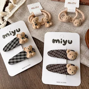 Detail of plaid fabric hair clips and elastic ties with cute beige flocked bear charms