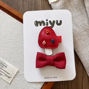 Close-up of red mushroom and bow hair clips on display card with rustic background