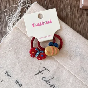 Close-up of red elastic hair ties with resin butterfly and cartoon beetle charms
