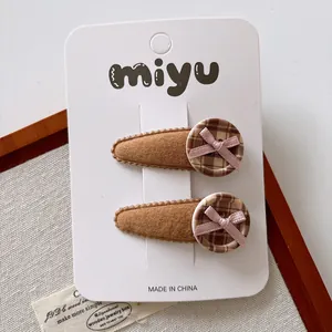 Detailed view of brown velvet teardrop hair clips with plaid buttons and pink bows