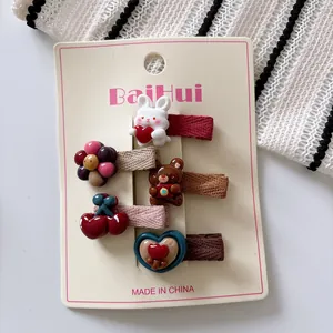 Close-up of 5-piece cartoon hair clips featuring rabbits and bears on a display card