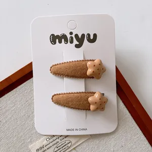 Detailed macro of two brown plush star hair clips on a white display card backing
