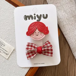 Detail of red cartoon girl and plaid bow hair clips on a white display card