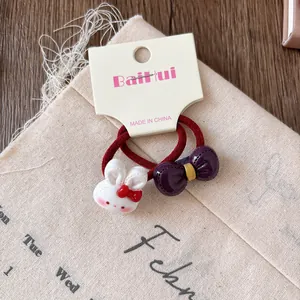 Detail view of a cute cartoon rabbit and purple bow on a red elastic hair band