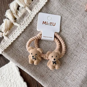 Close-up of cute flocked bear hair ties in brown with bows on branded card