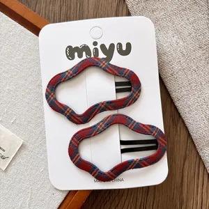 Détail des barrettes BB ondulées avec texture de tissu à carreaux rouge et bleu
