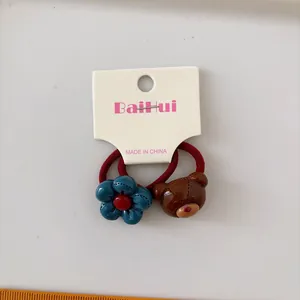 Set of two elastic kids hair ties with blue flower and brown bear cartoon charms
