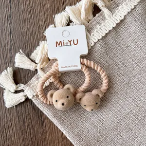 Detail of two cute flocked bear hair ties with spiral elastic bands on linen fabric