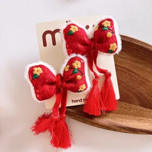 Detalle de pinzas para el cabello rojas con borlas, bordado floral y borde de piel sintética