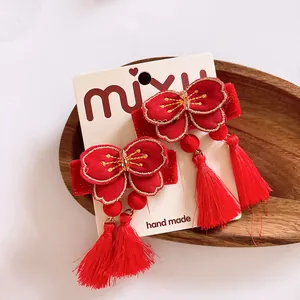 Detalle de pinzas para el cabello con flores rojas bordadas y borlas colgantes