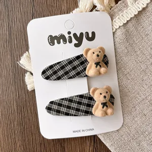 Detail of cute flocked teddy bear hair clips with black and white plaid fabric on metal base