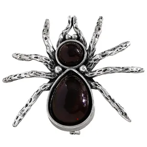 Detail of vintage spider brooch with deep red gemstones and antique silver texture