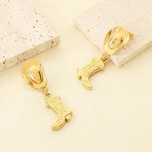 Detail shot of gold-plated cowboy hat and boot earrings on textured stone props