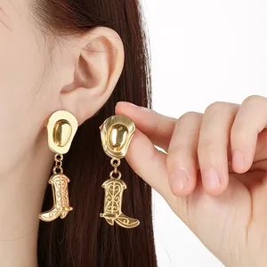 Close-up of golden stainless steel cowboy hat and boot dangle earrings on model's ear