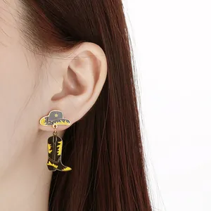 Close-up detail showing a western cowboy hat and boot dangle earring worn on a model ear