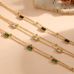 Macrodetail van een dubbellaagse gouden armband met groene en zwarte vierkante stenen