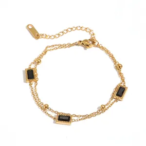 Detailopname van een gouden dubbellaagse roestvrijstalen armband met vierkante zwarte stenen