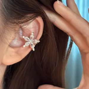 Close-up of a sparkling star-shaped ear cuff with brilliant zircon stones on model's ear