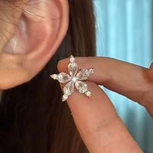 Detail macro view of a sparkling cubic zirconia star-shaped ear cuff held near an ear