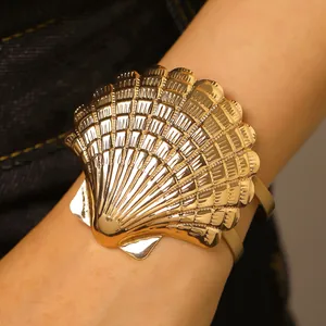 Close-up of gold shell armlet with detailed metallic texture and adjustable cuff design
