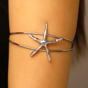 Detail view of a silver textured starfish arm cuff bracelet worn on an upper arm