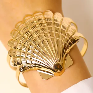 Close-up of a large gold seashell adjustable arm cuff bracelet for beach vacations.