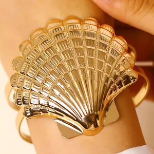 Close-up detail of a polished gold seashell adjustable arm cuff for beach vacation