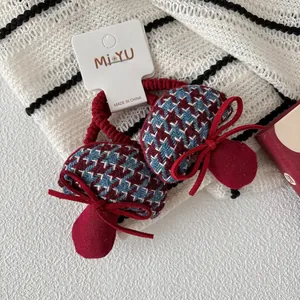 Detalle de coleteros con forma de seta y lazos rojos con diseño de pata de gallo