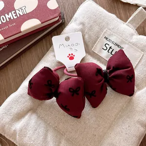 Close-up of red plaid bow hair ties with black patterns on a branded display card