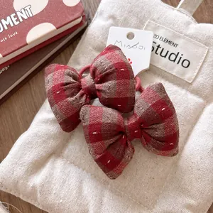 Close-up of red checkered cotton bow hair ties with detailed stitching on fabric