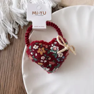 Detail of red floral velvet heart scrunchie with bow tie and vintage floral print