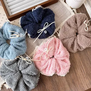 Detail of five plush lace scrunchies with white buttons on a wooden tray