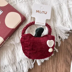 Detail of red apple velvet hair scrunchie with leaf and white heart on display card