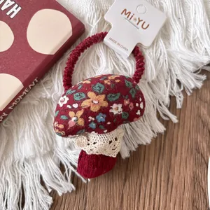 Detailed view of a red floral mushroom hair tie with white lace on a cozy textile
