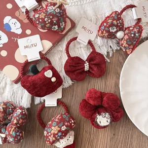 Close-up of red floral velvet hair scrunchies with cute bows and festive embroidery