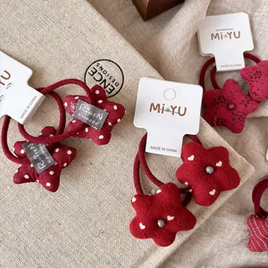 Coleteros de tela rojos con diseños de estrellas y flores con lunares blancos en tarjeta