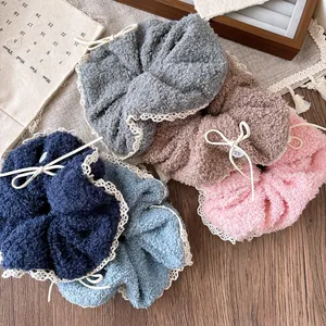 Close-up of plush hair scrunchies with white lace edges and decorative bow buttons