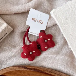Detalle de gomas de pelo de flores de peluche rojo con corazones en fondo de tela