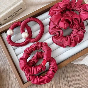 Detail of burgundy satin scrunchies and pearl hair ties on a vintage display tray