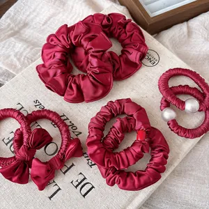 Macro shot of burgundy satin bow hair tie and scrunchie with elegant pearl details
