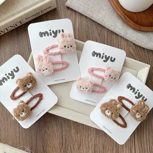 Close-up of cute plush bear and rabbit hair clips displayed on white paper cards