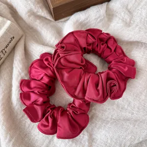 Detailed view of ruffled burgundy satin hair scrunchies with elegant glossy texture
